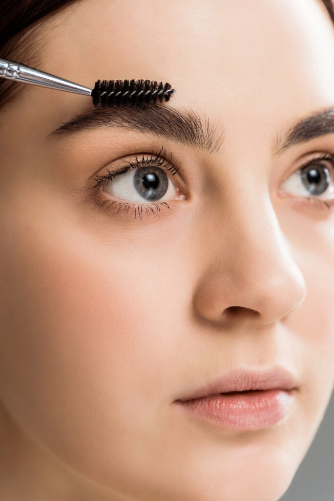 beautiful young woman styling eyebrow with eyebrow brush